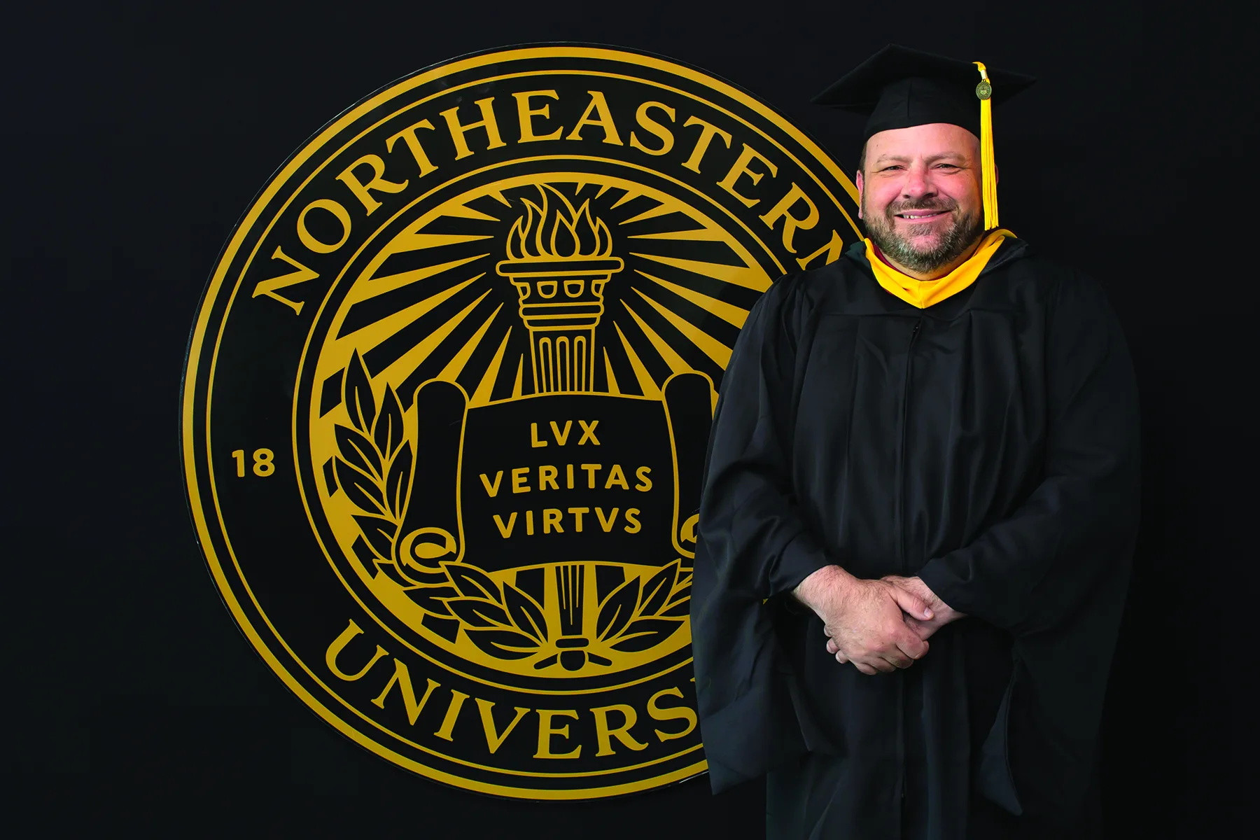 A graduate portrait in front of the Northeastern University seal